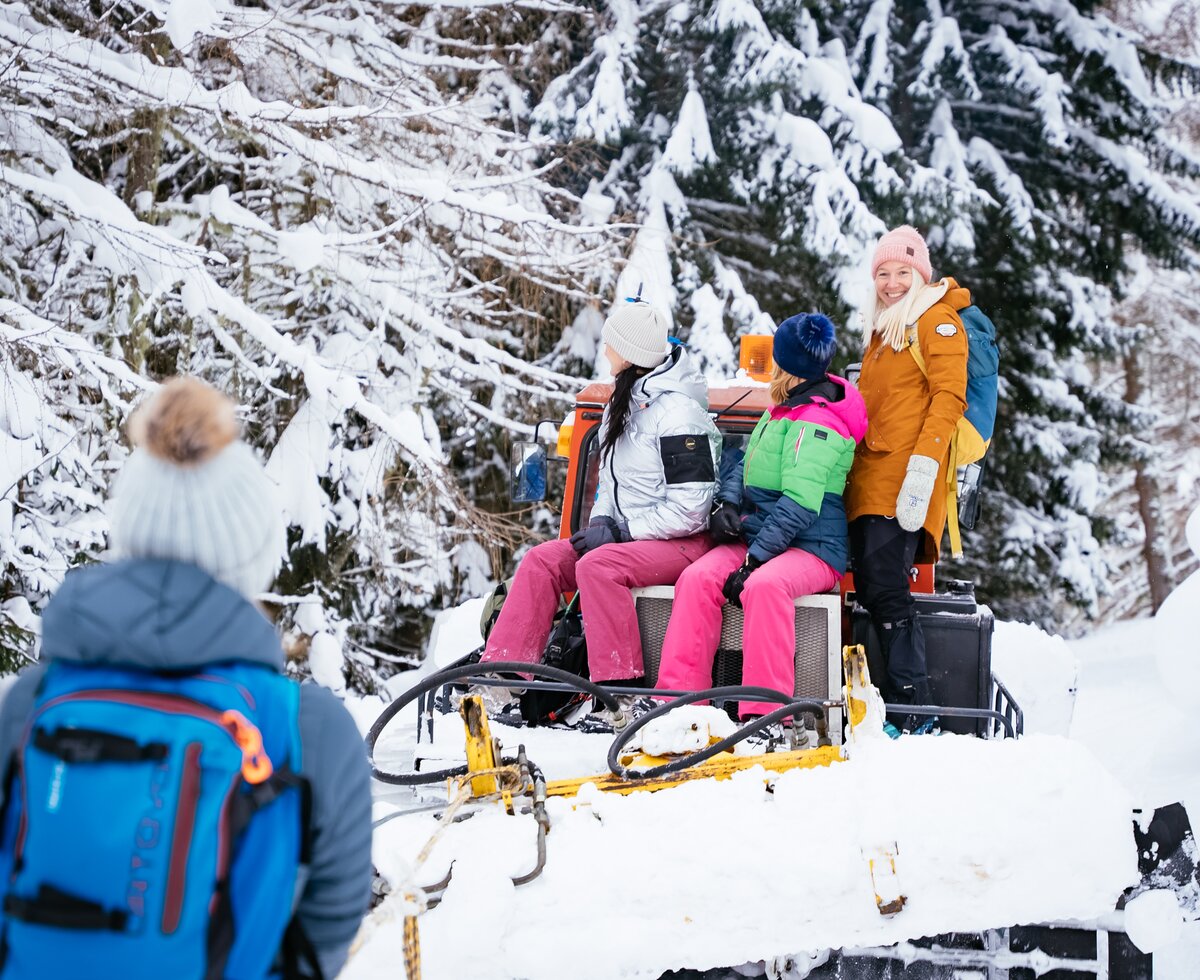 Mädels sitzen am Pistengerät und schauen in den verschneiten Wald | © Urlaub am Bauernhof Kärnten/ Daniel Gollner