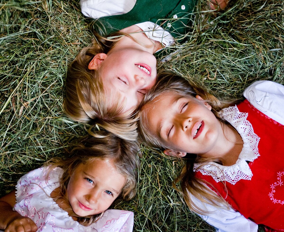 Drei Kinder liegen im Heu | © Urlaub am Bauernhof Kärnten / Tom Lamm