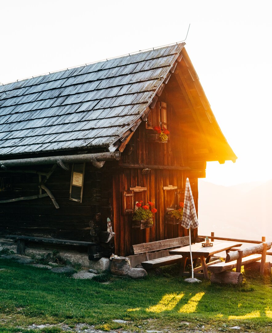 Die Almhütte scheint im Morgenlicht bei der aufgehenden Sonne in Kärnten | © Urlaub am Bauernhof Kärnten / Daniel Gollner