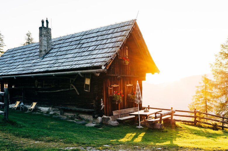 Die Almhütte scheint im Morgenlicht bei der aufgehenden Sonne in Kärnten | © Urlaub am Bauernhof Kärnten / Daniel Gollner