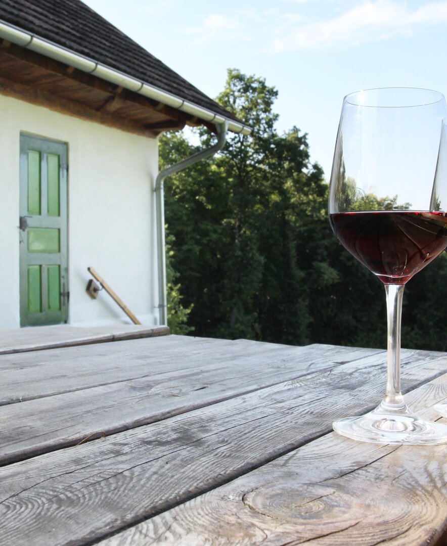 2 Gläser mit Rotwein auf Holztisch vor dem Weinkeller | © Urlaub am Bauernhof Burgenland / Wolfgang Pummer