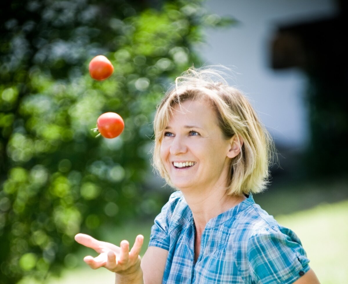 Frau jongliert mit 2 Tomaten im Garten | © Urlaub am Bauernhof Burgenland / Andi Bruckner 