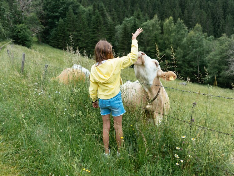 Ein Mädchen steht vor einer Kuh.  | © Urlaub am Bauernhof Kärnten/ Angelina Tschische