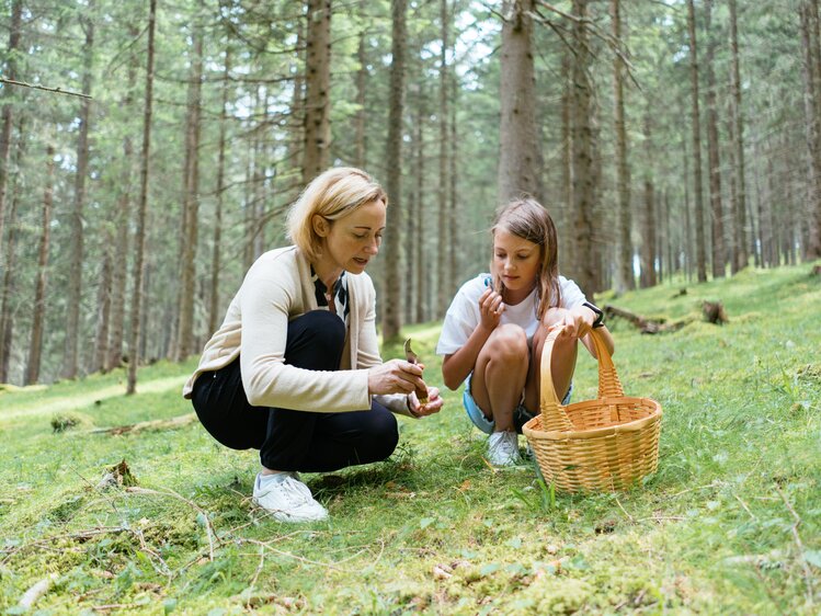 Gerhild und ihre Tochter hocken am Waldboden und sammeln Pilze.  | © Urlaub am Bauernhof Kärnten/ Angelina Tschische