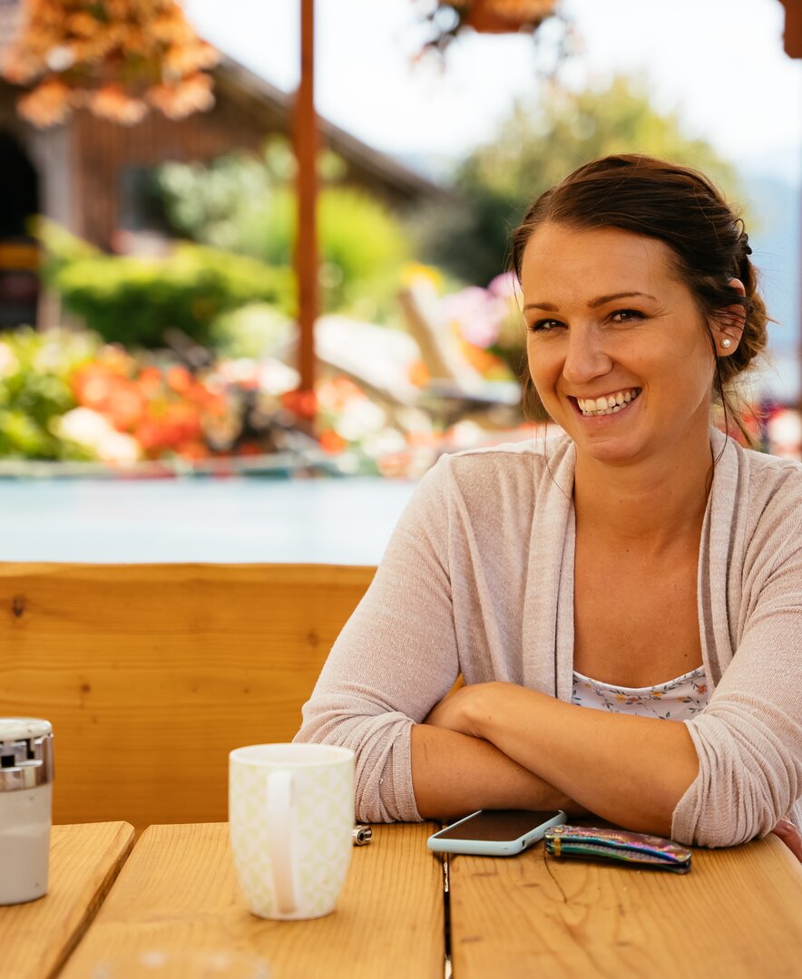 Stefanie Ofner sitzt am Tisch und erzählt von ihrem Leben am Bauernhof | © Urlaub am Bauernhof Kärnten / Daniel Gollner