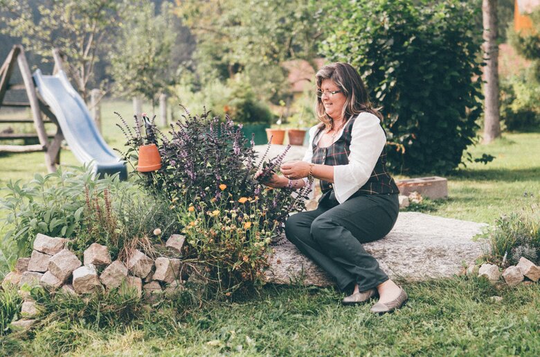 Frau sitzt bei Kräutern | © Urlaub am Bauernhof Kärnten/Daniel Gollner