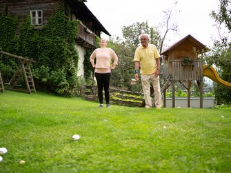 Mann und Frau spielen im Garten mit Kugeln | © Urlaub am Bauernhof Kärnten / Daniel Gollner