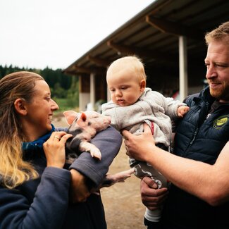 Familie mit Babyschwein in der Hand | © Urlaub am Bauernhof Kärnten/ Daniel Gollner