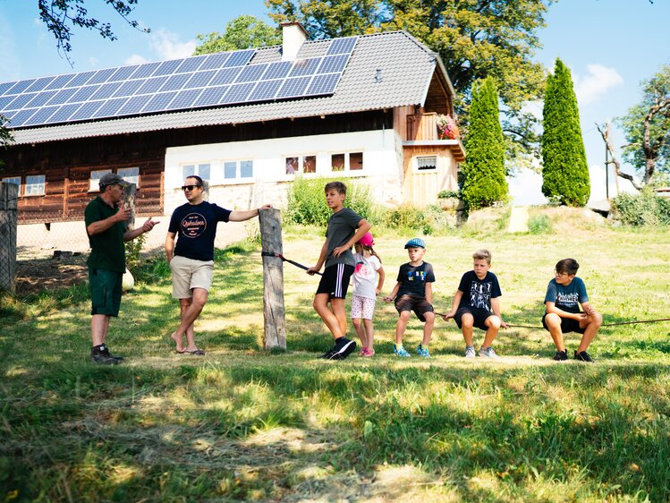 Familie steht und sitzt auf der Wiese | © Urlaub am Bauernhof Kärnten / Daniel Gollner