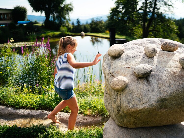 Kind geht über die Steine am Teich | © Urlaub am Bauernhof Kärnten / Daniel Gollner