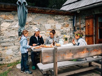 Familie isst am Tisch vor der Hütte | © Urlaub am Bauernhof Kärnten / Daniel Gollner