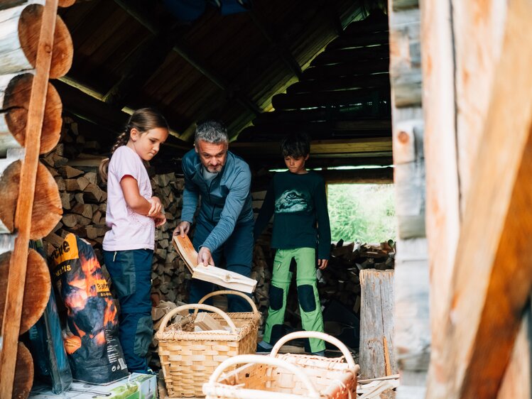 Mann und Kinder holen Holz in der Hütte | © Urlaub am Bauernhof Kärnten/ Daniel Gollner