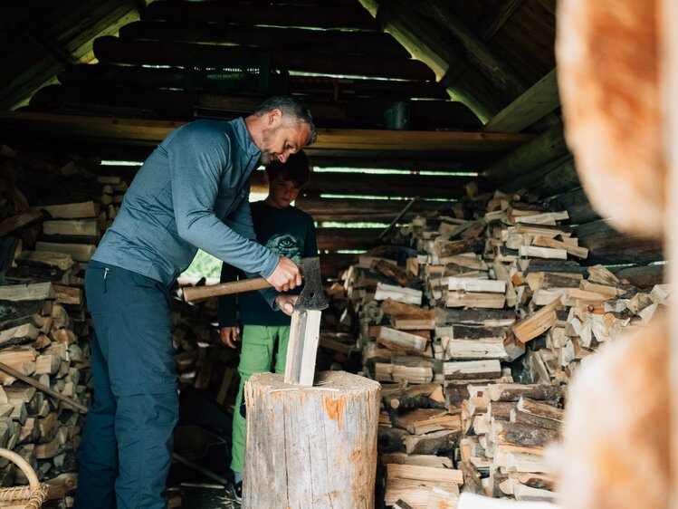 Mann spaltet Holz in der Hütte | © Urlaub am Bauernhof Kärnten / Daniel Gollner