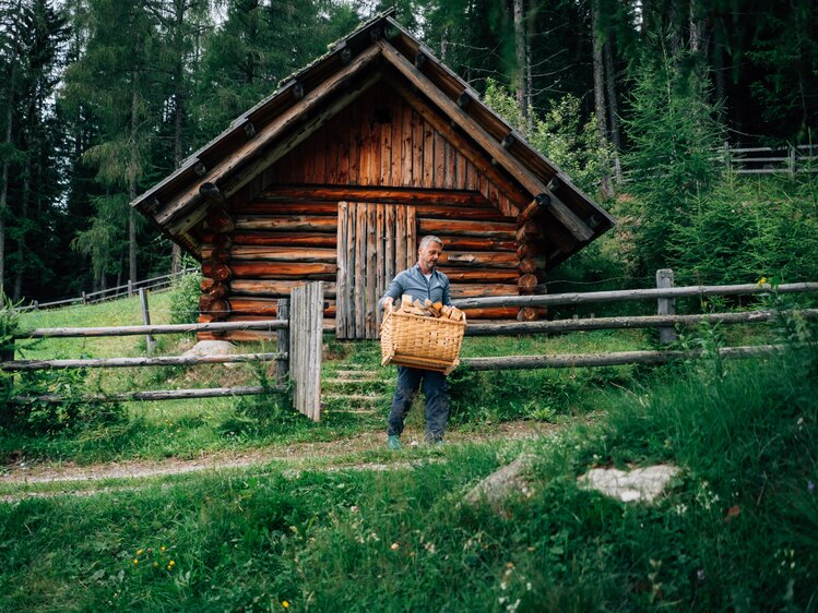 Mann trägt das Holz in einem Korb | © Urlaub am Bauernhof Kärnten / Daniel Gollner