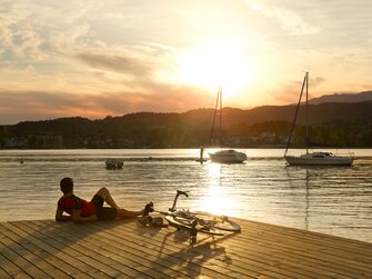 Rennradfahrer macht gerade Pause bei untergehender Sonne am See | © Franz Gerdl / Kärnten Werbung GmbH