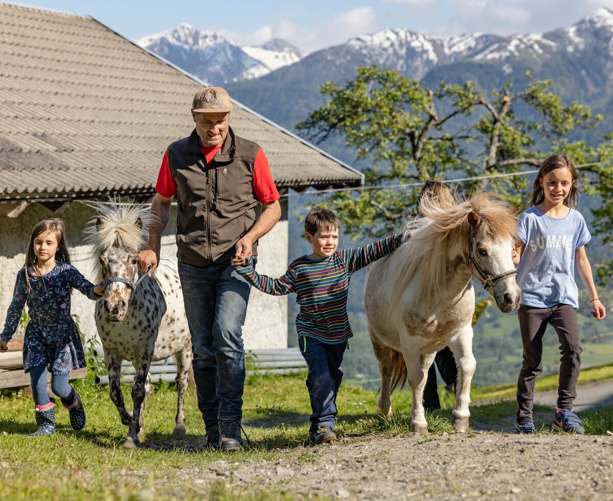 Bauer und Kinder gehen mit den Ponys | © Landesverband Urlaub am Bauernhof Kärnten/ Achim Mandler