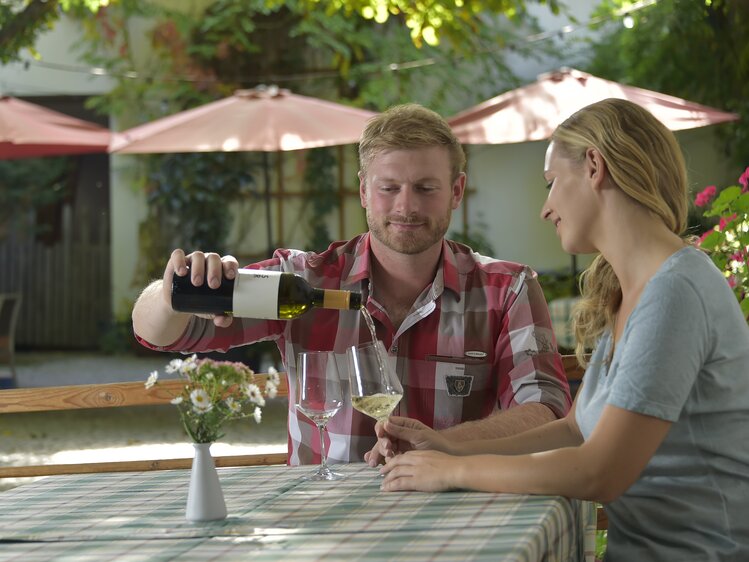 Paar sitzt beim Heurigen und trinkt Wein | © Urlaub am Winzerhof / Ralph Fischbacher