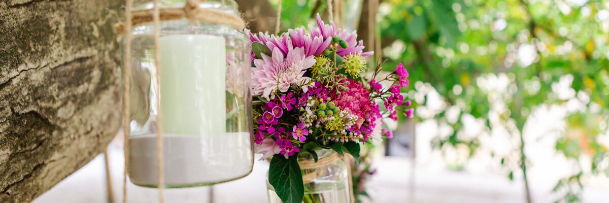 Kerzen und Blumen hängen in einem Glas am Baum | © Urlaub am Winzerhof / Marie & Michael Photography - www.marieundmichael.com