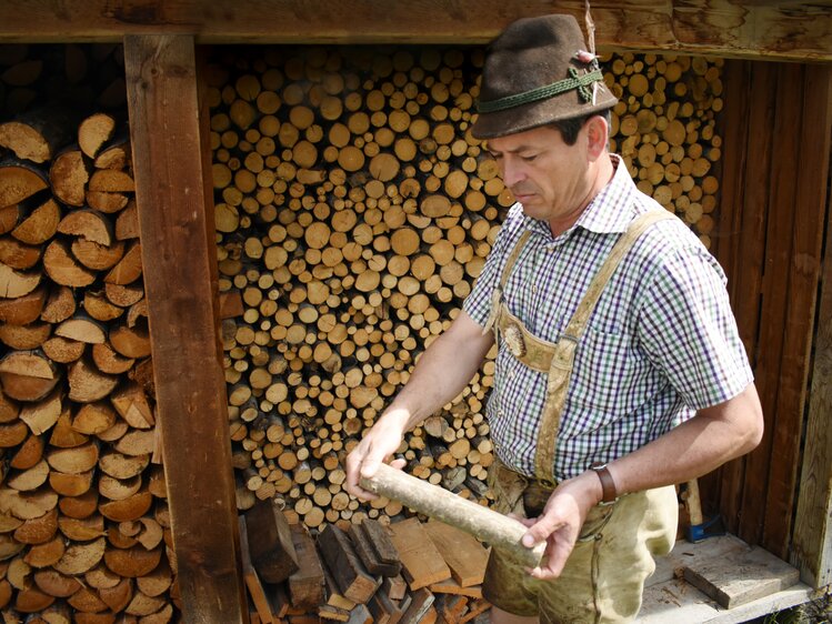 Bauer zeigt ein Stück Holz her | © Urlaub am Bauernhof Oberösterreich / Harald Puchegger