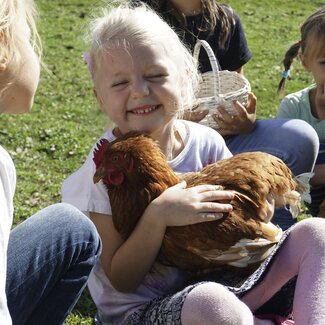 Kind hält ein Huhn auf dem Arm und streichelt es | © Urlaub am Bauernhof Oberösterreich / Harald Puchegger