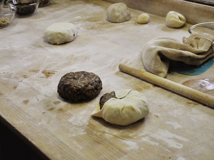 Zwei Laibe Kletzenbrot liegen auf der Arbeitsfläche und werden in Teig eingeschlagen | © Urlaub am Bauernhof Oberösterreich / Harald Puchegger