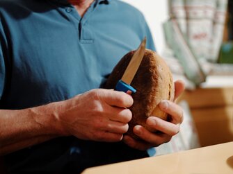 Ein Laib Brot wird vor dem Anschneiden gesegnet | © Urlaub am Bauernhof Oberösterreich / Daniel Gollner