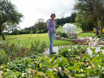 Bäuerin steht in ihrem Kräutergarten am Bauernhof | © Urlaub am Bauernhof Oberösterreich / Daniel Gollner