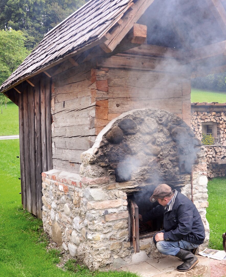 Bauer heizt das traditionelle Dörrhäusl zum Obst dörren ein | © Urlaub am Bauernhof Oberösterreich / Harald Puchegger