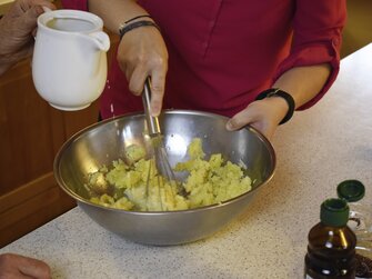 Köchin verrührt zerdrückte Erdäpfel mit Milch | © Urlaub am Bauernhof Oberösterreich / Harald Puchegger