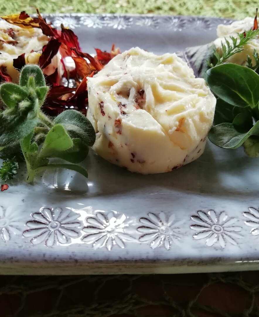 Bunte Blütenbutter angerichtet auf einem Teller mit frischen Kräutern | © Urlaub am Bauernhof Oberösterreich / Annemarie Reifeltshammer