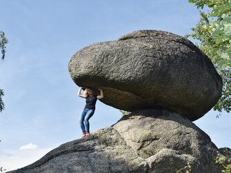 Frau versucht an einem riesigen Wackelstein zu wackeln | © Urlaub am Bauernhof Oberösterreich / Harald Puchegger