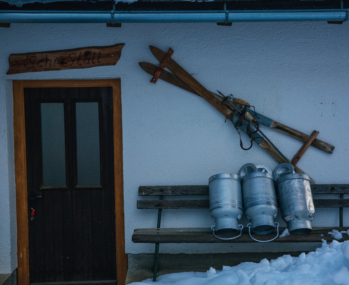 Alte Holzski und Milchkannen vor dem Skistall | © Urlaub am Bauernhof Oberösterreich / Pascal Baronit