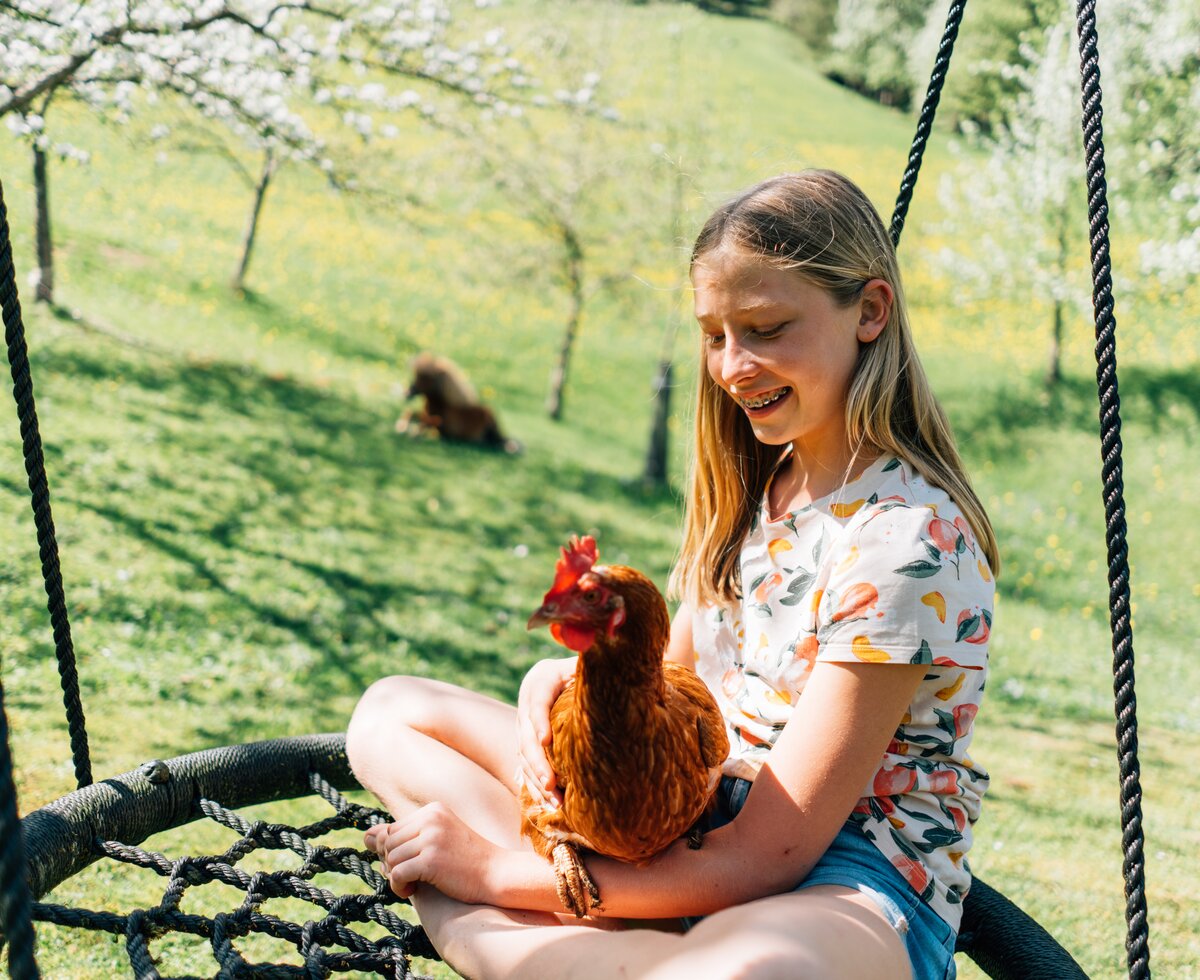 Mädchen mit Huhn auf der Schaukel | © Urlaub am Bauernhof / Daniel Gollner 