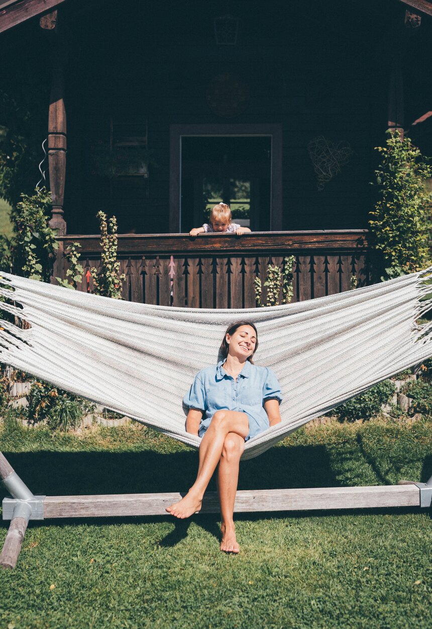 Frau in Haengematte und Kind schaut von Balkon | © Urlaub am Bauernhof / Daniel Gollner