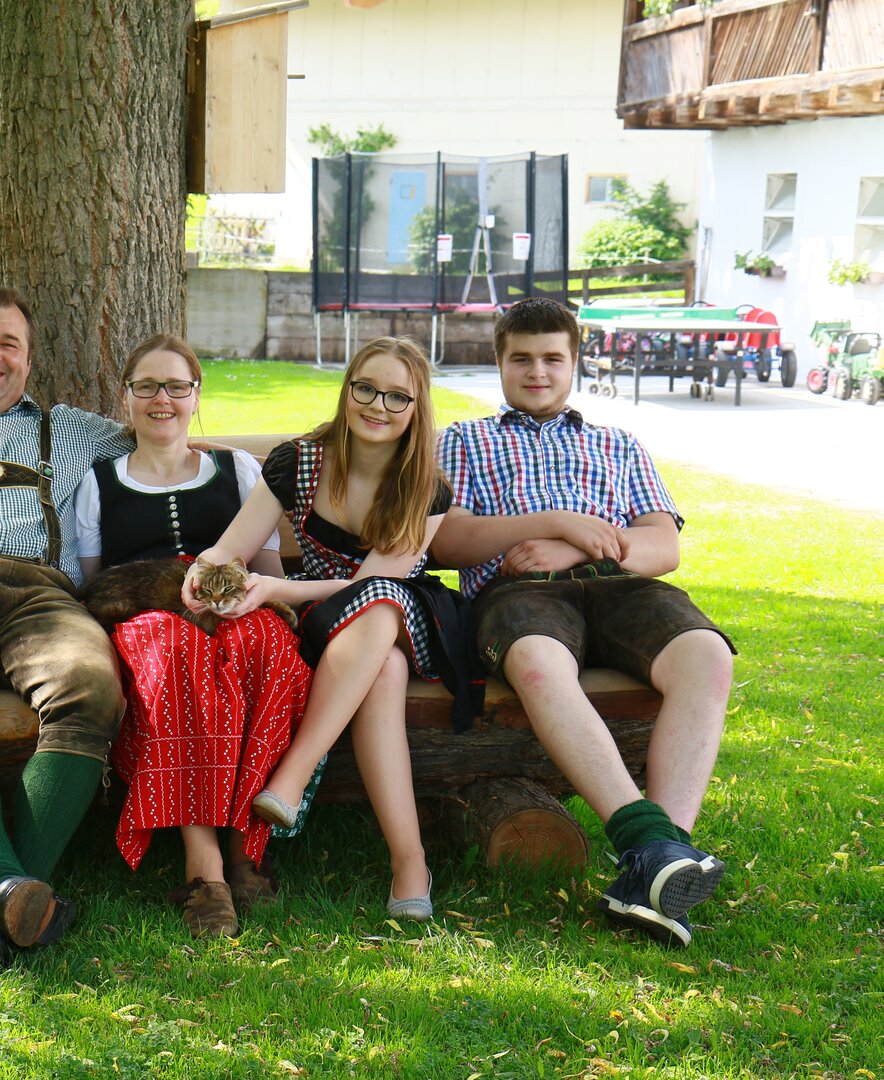 Familie Kerschbaumer sitzt auf Holzbank im Garten am Hönigshof | © Urlaub am Bauernhof Österreich / Wolfgang Baumgartner