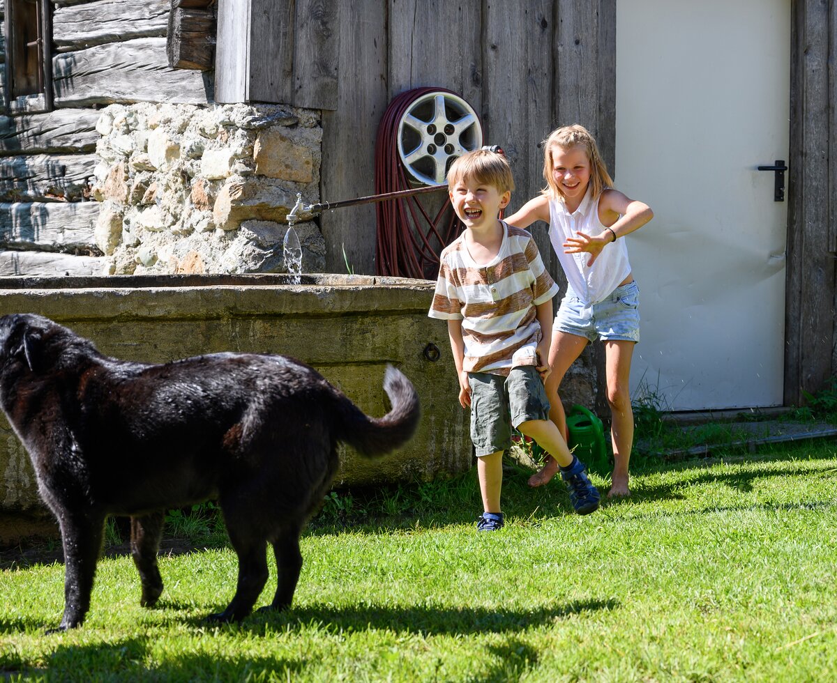 Kinder toben mit Hund durch den Garten | © Katja Stadler / Urlaub am Bauernhof