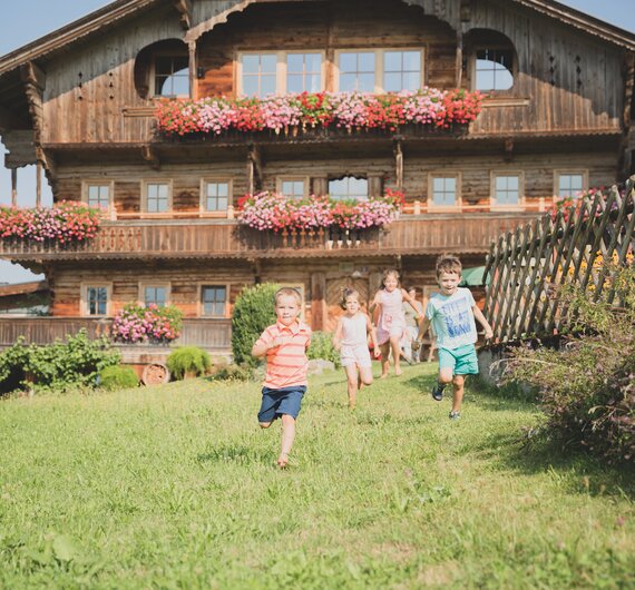 4 Kinder laufen vor Bauernhof | © Urlaub am Bauernhof Österreich / Pascal Baronit