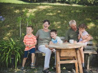 Großeltern mit 3 Enkeln auf Sitzbank im Freien | © Urlaub am Bauernhof Österreich / Pascal Baronit