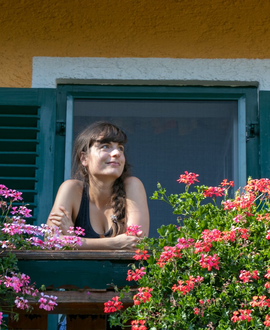 Frau auf blumengeschmücktem Balkon | © Urlaub am Bauernhof im SalzburgerLand / www.travelpins.at