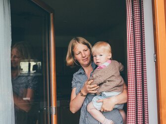 Bäuerin Kathrin Röck vom Grußberggut in Bad Hofgastein hält ihr Baby am Arm | © Urlaub am Bauernhof im SalzburgerLand / Daniel Gollner