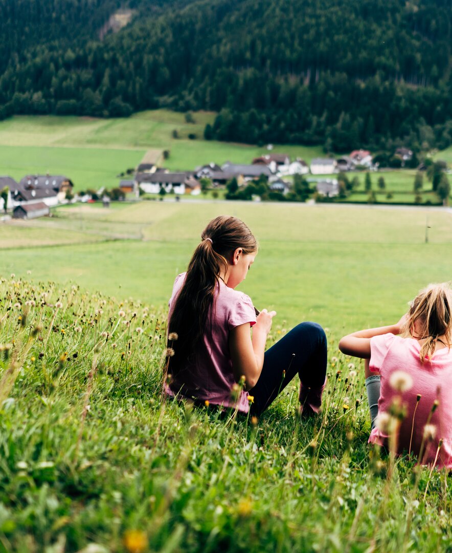 Zwei Mädchen sitzen in der Wiese | © Urlaub am Bauernhof im SalzburgerLand / Daniel Gollner