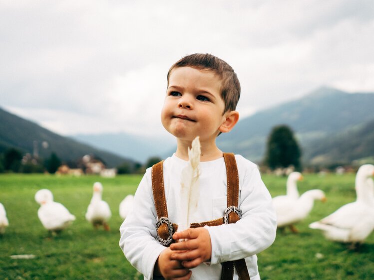 Ein Bub spielt mit einer Gänsefeder. | © Urlaub am Bauernhof im SalzburgerLand / Daniel Gollner