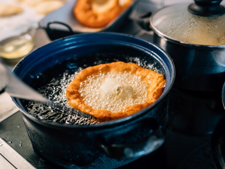 Ein goldbrauner Bauernkrapfen wird in heißem Fett herausgebacken. | © Urlaub am Bauernhof im SalzburgerLand / Daniel Gollner