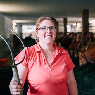 Bäuerin Maria Höpflinger steht in ihrem Stall und hat die Heugabel in der Hand. | © Urlaub am Bauernhof im SalzburgerLand / Daniel Gollner