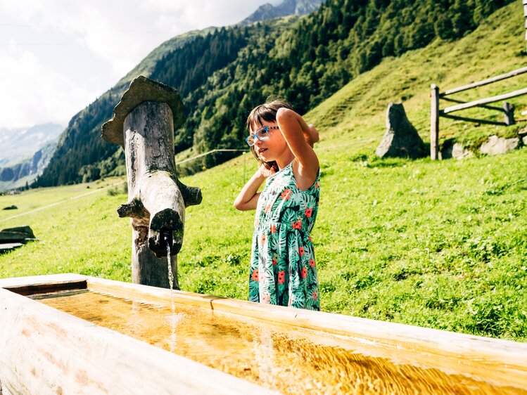 Ein Mädchen steht am Brunnen auf der Scharreralm im Nationalpark Hohe Tauern. | © Urlaub am Bauernhof im SalzburgerLand / Daniel Gollner