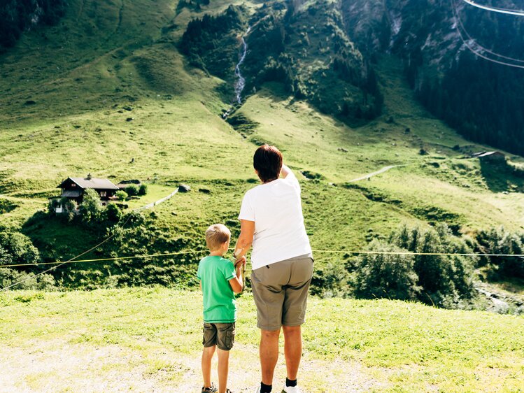 Eine Mutter zeigt ihrem Sohn den Wasserfall auf der Alm. | © Urlaub am Bauernhof im SalzburgerLand / Daniel Gollner