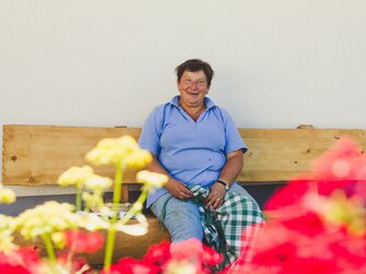 Gastgeberin Karin Pöllmann vom Stallerbauer in Ried am Wolfgangsee sitzt auf dem Hausbankerl. | © Urlaub am Bauernhof im SalzburgerLand / Matthias Gruber