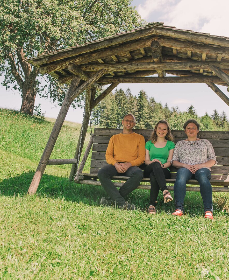 Familie sitzt mitten auf der Wiese auf einer Schaukel | © Urlaub am Bauernhof Steiermark / Sabine Ertl