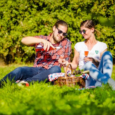 Ein paar sitzt im Weingarten beim Picknick und schenkt sich Schilcherfrizzante ein, Süd-West-Steiermark, Steiermark | © Urlaub am Bauernhof Steiermark / Wolfgang Spekner