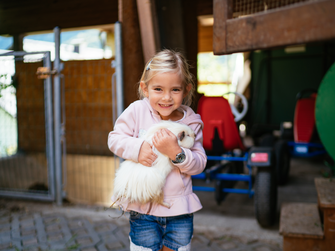 Ein Kind hält ein weißes Meerschweinchen in der Hand | © Urlaub am Bauernhof / Daniel Gollner